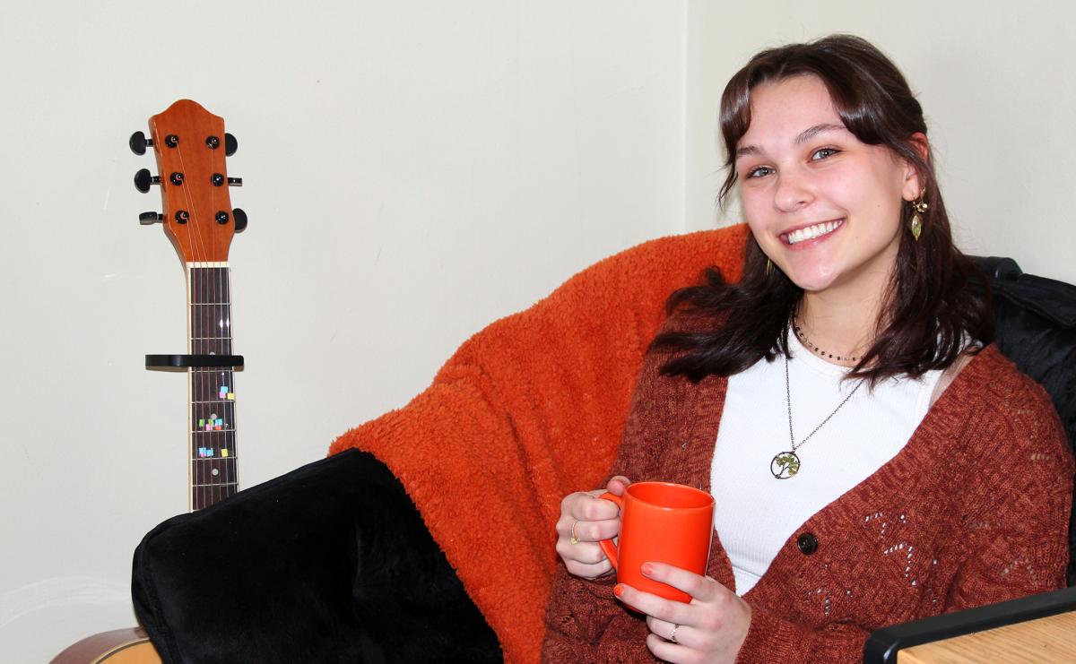 students sits in her dorm room with a warm drink