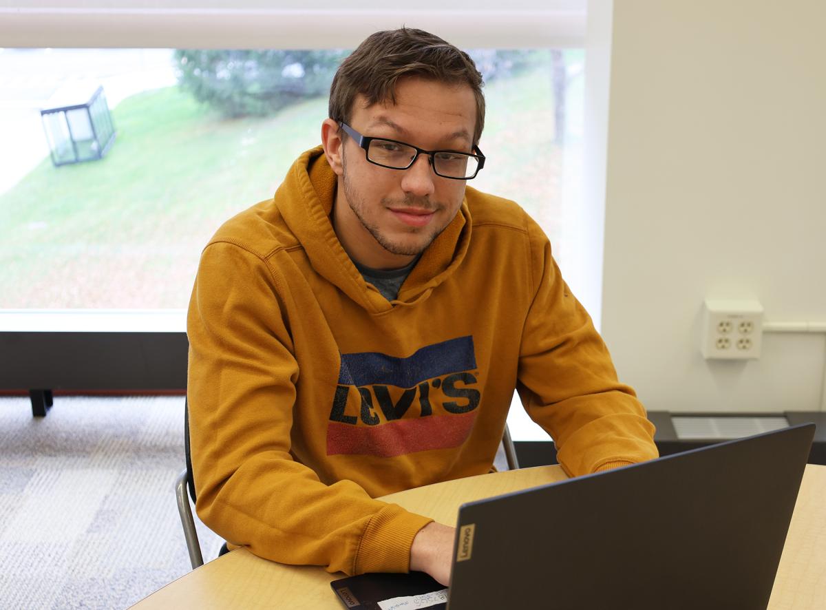 Student sits behind laptop