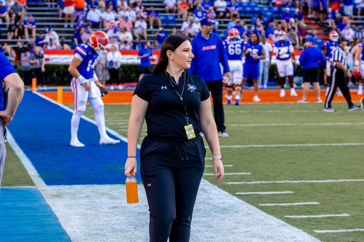 Alfred State alum Kelsey Curry walks the sideline prior to the start of a McNeese State football game at Florida.
