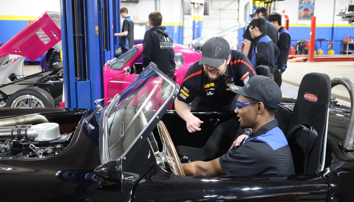 Instructor with student working on a car