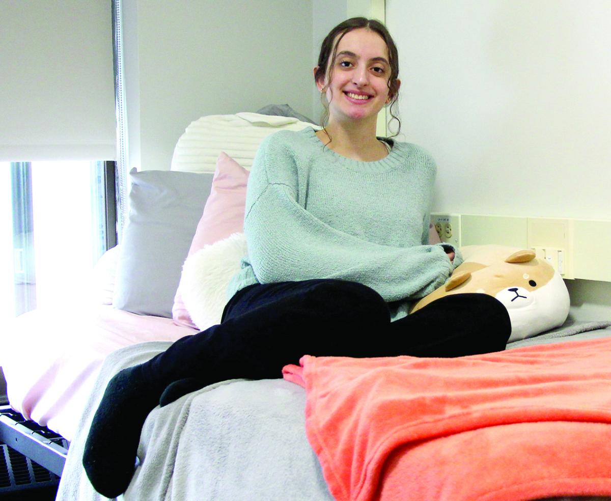 Gabriela Leite sits on her bed in her dorm room