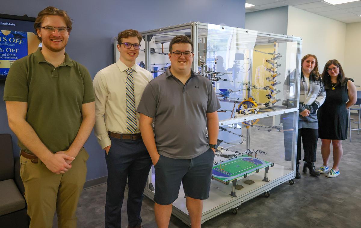 students stand with the marble run machine