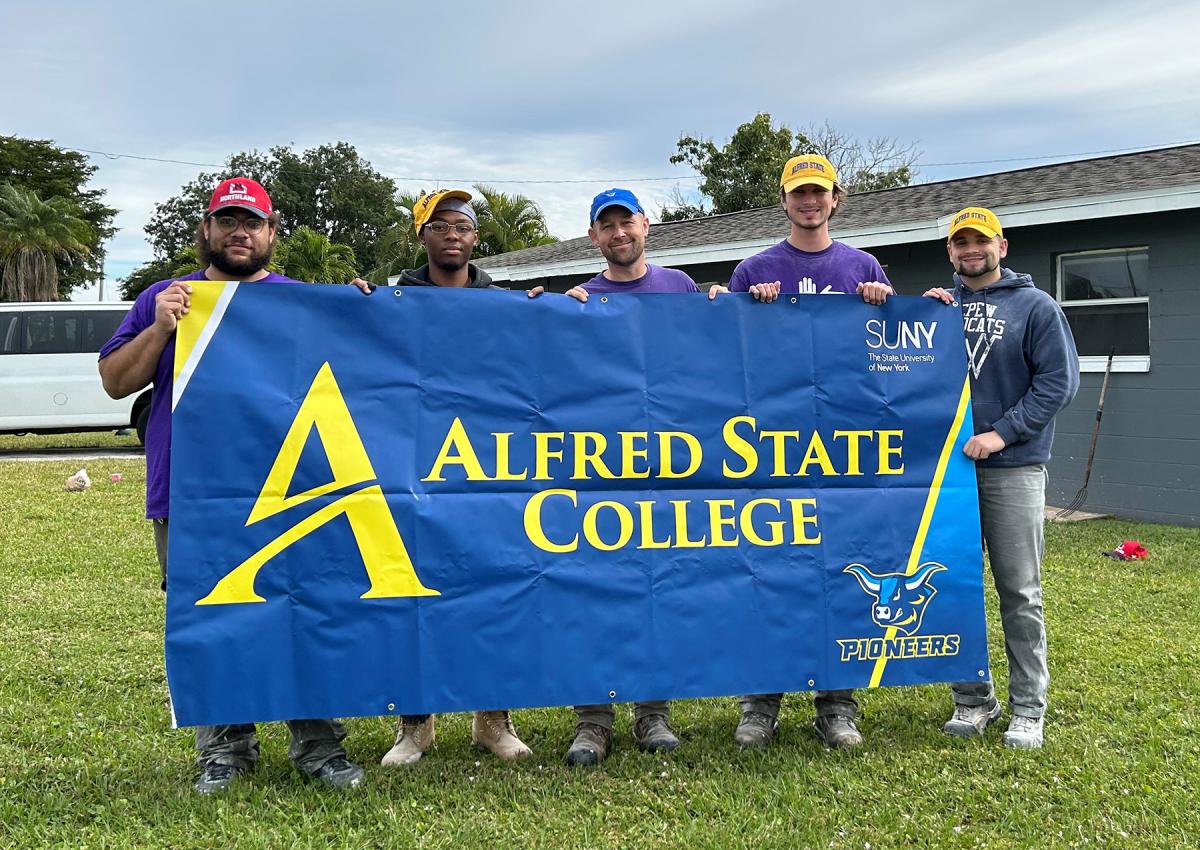 A group of Alfred State students hold a college sign