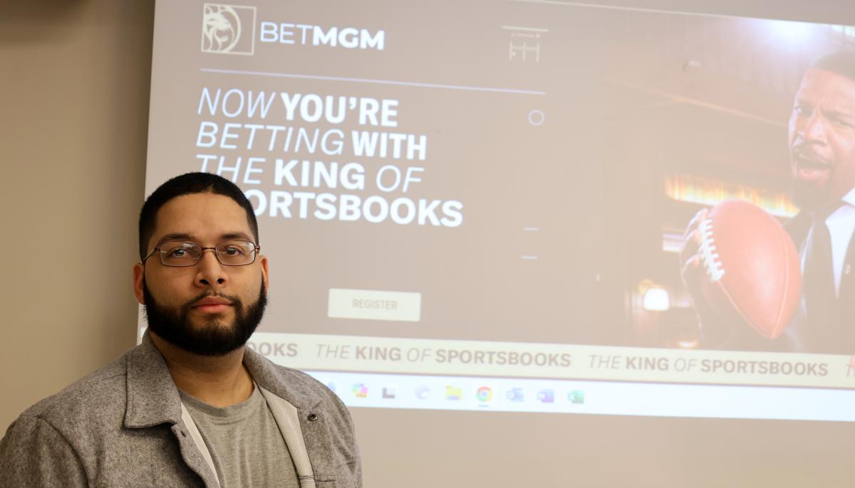 alumni stands in front of company advertisement