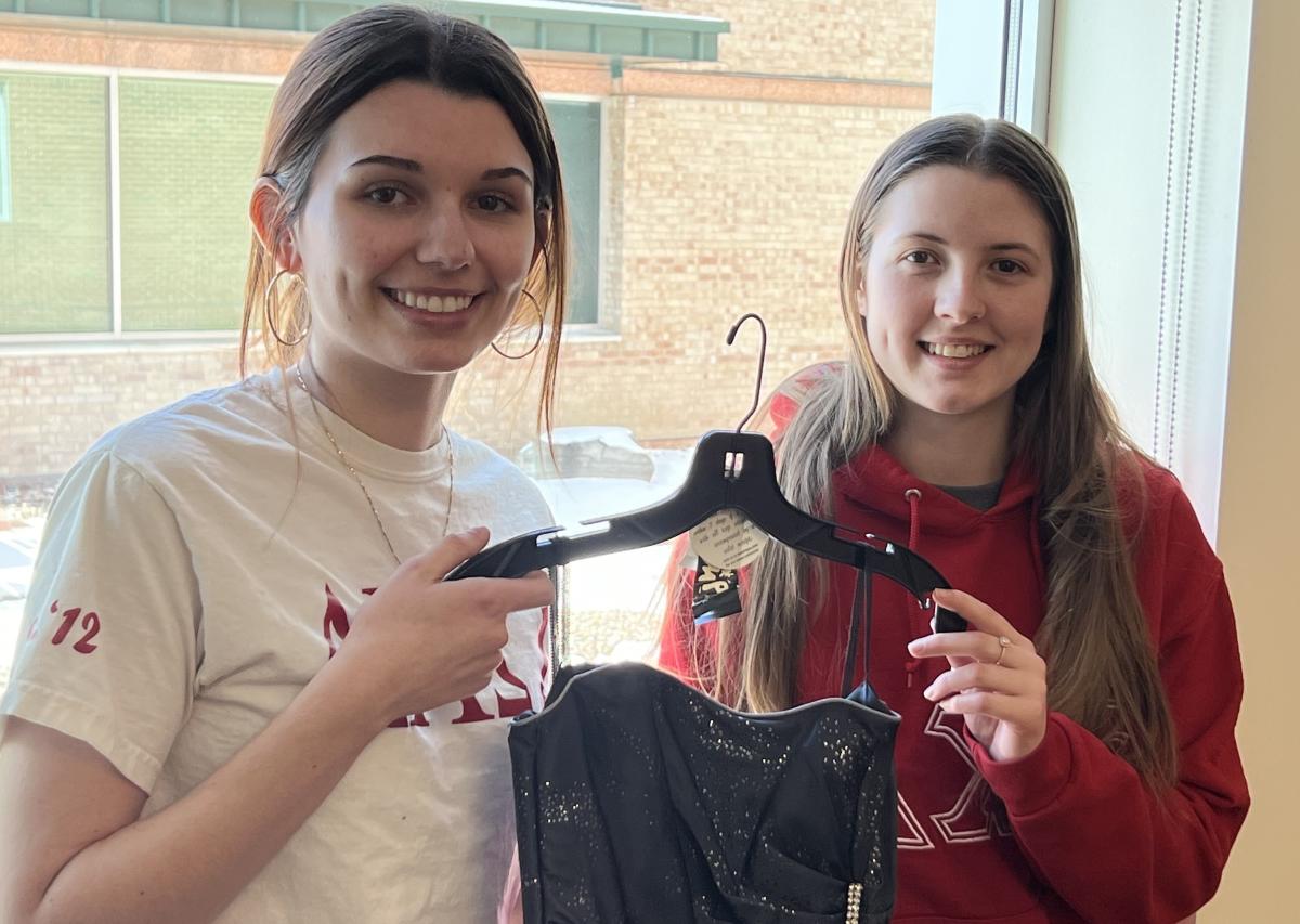 Pair of Delta Chi Omega sisters hold up a dress