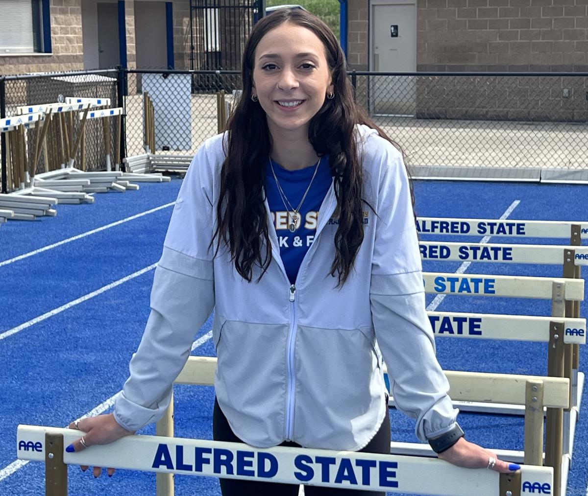 Student standing in between hurdles on the track.