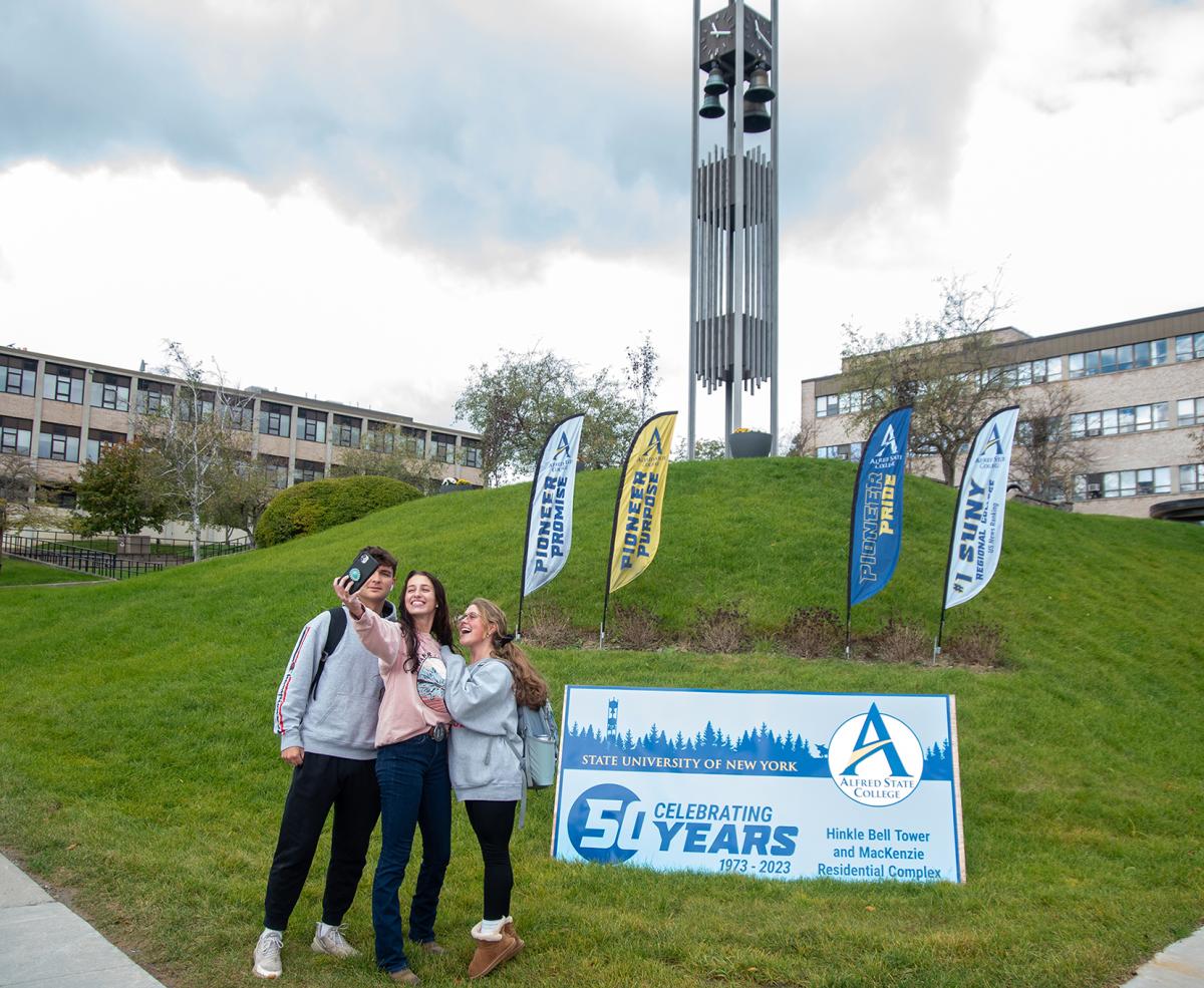 students pose in front of a bell tower