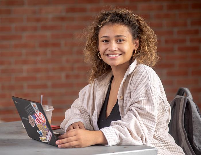 An Alfred State student works on her laptop outside.