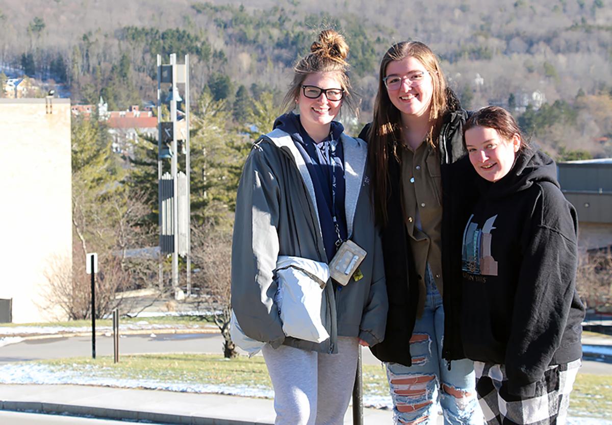 Alfred State students pose for a picture with the bell tower in the background.