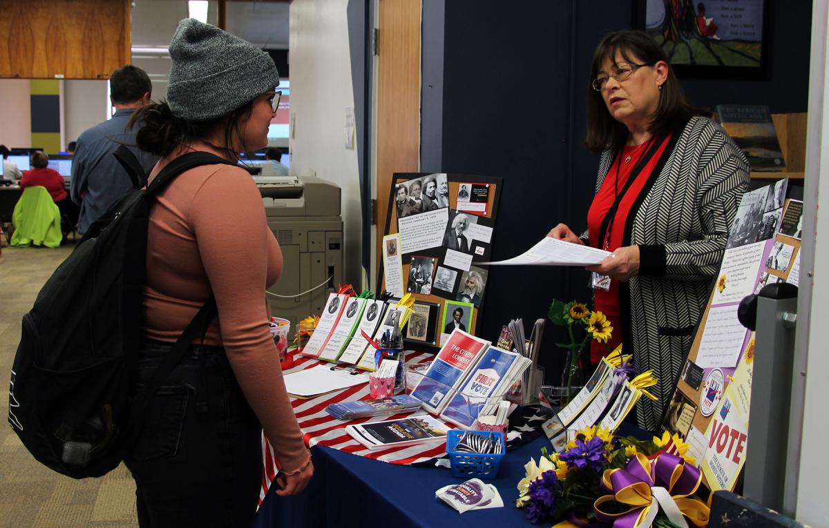 An Alfred State student speaks with a representative from the League of Women Voters during the Douglass Day celebration.