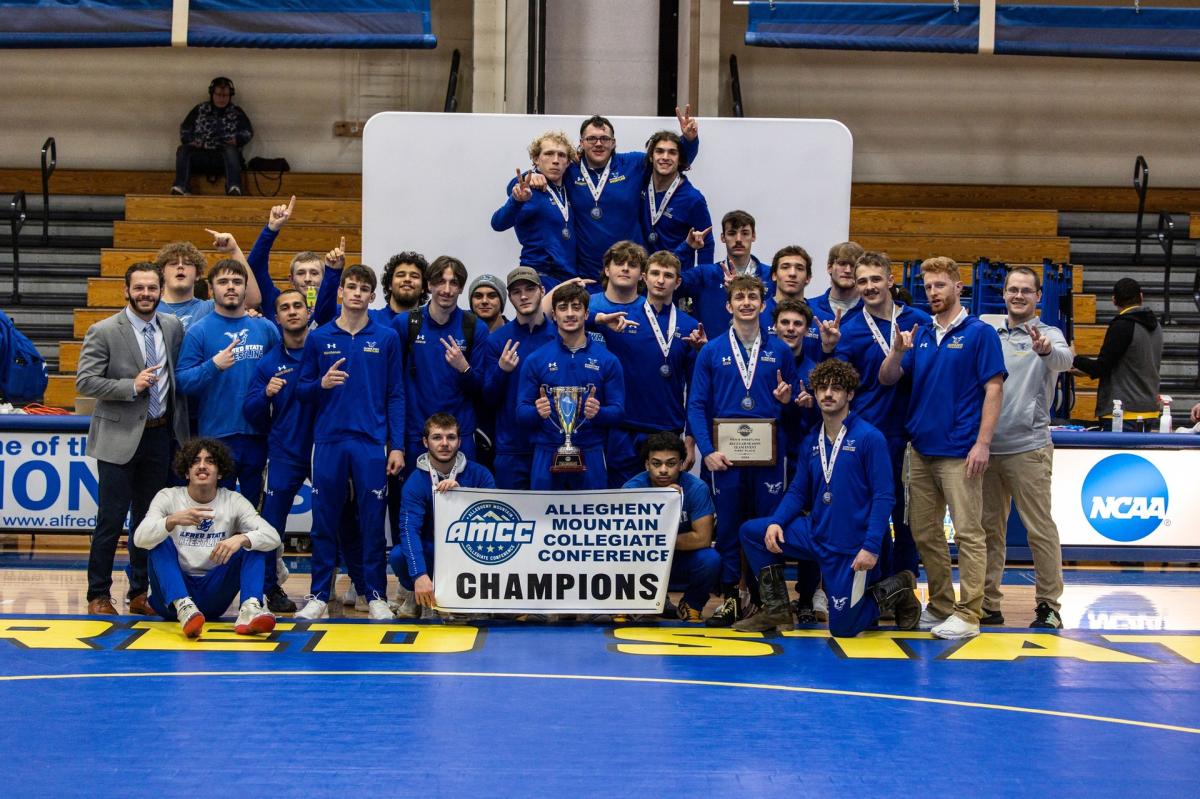 Alfred State wrestling team poses with championship banner and trophy