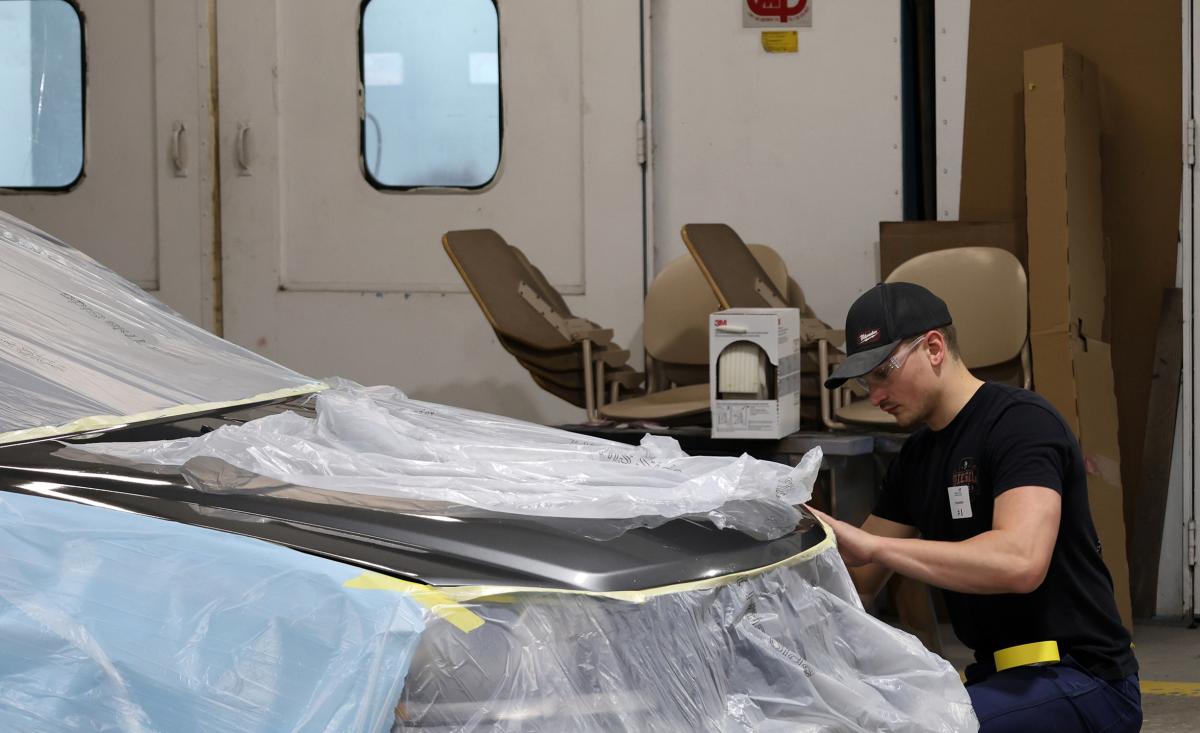 student works on the body of a car