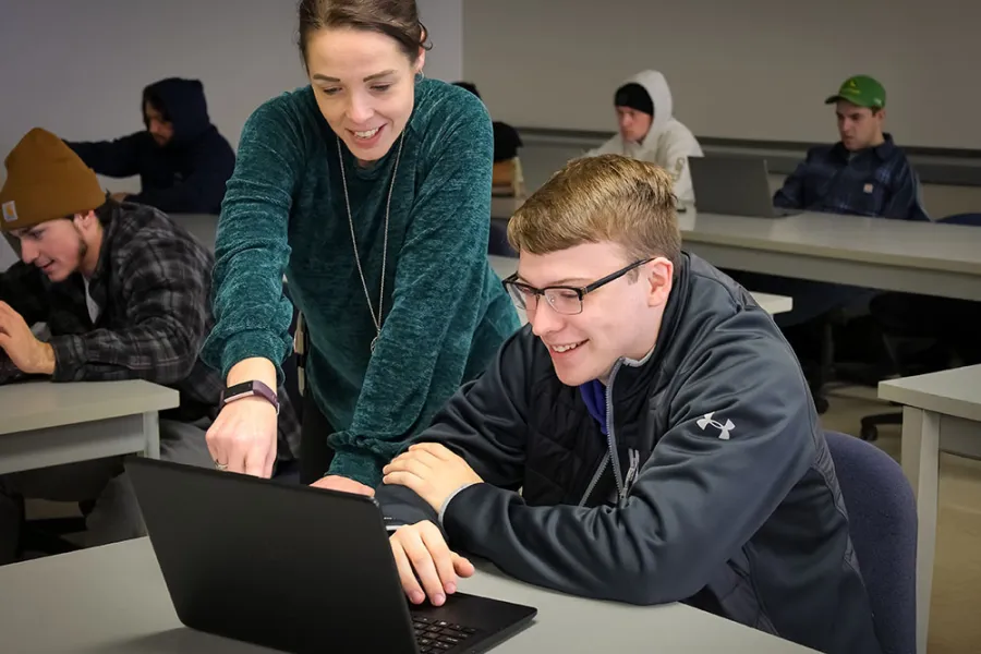 A student receiving guidance from a professional staff member while looking at a computer.