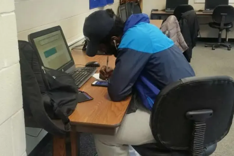 Student sitting at desk in front of computer working on assignment.