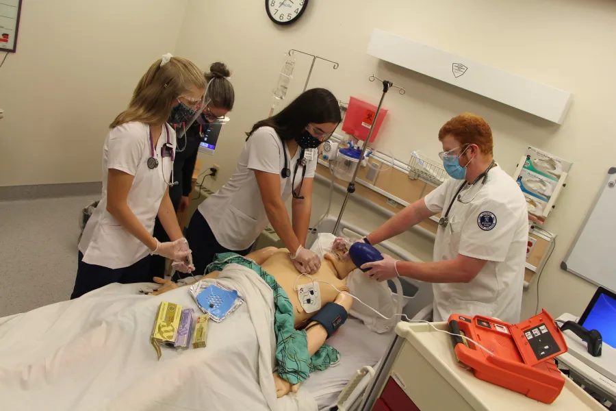 Nursing students practicing on medical manikin.