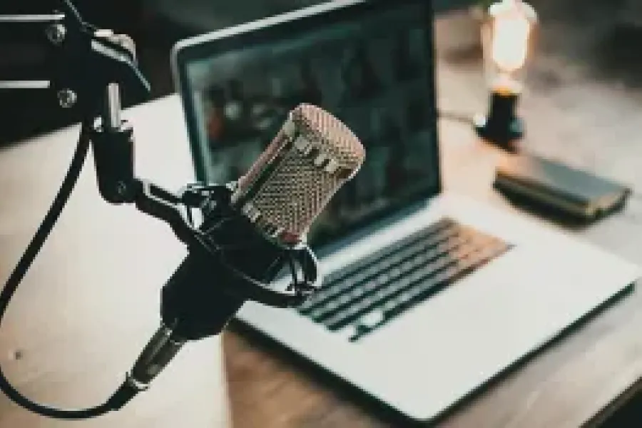 Microphone with laptop sitting on desk in the background.