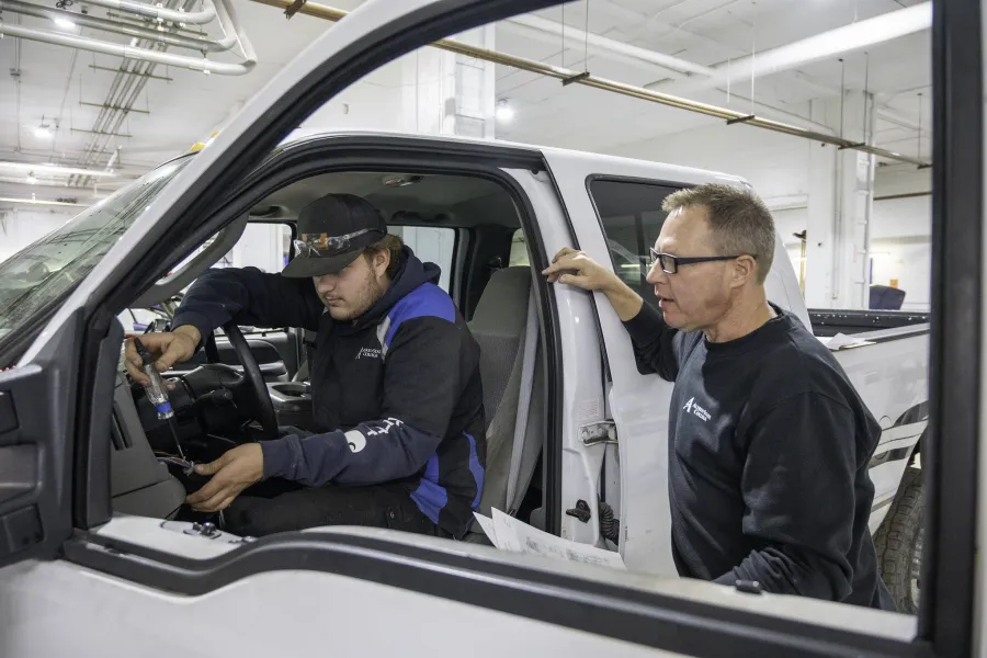 a student and professor working on a vehicle