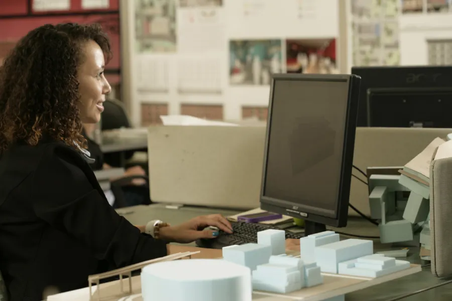 A student working at a computer in front of architectural models.