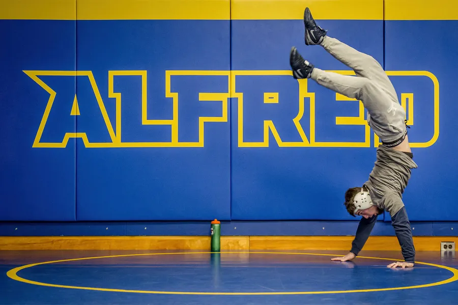 Photo of an ASC athlete doing a handstand in front on an Alfred State mural.