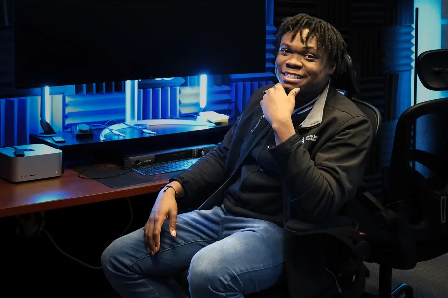 Photo of a male ASC student sitting in a dim production studio.