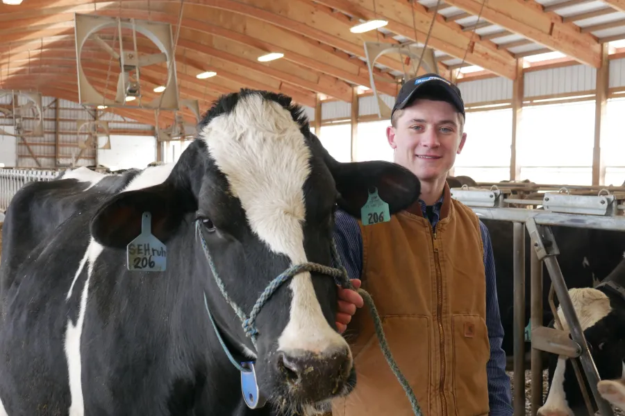 Agricultural technology student posing for a picture with a cow.