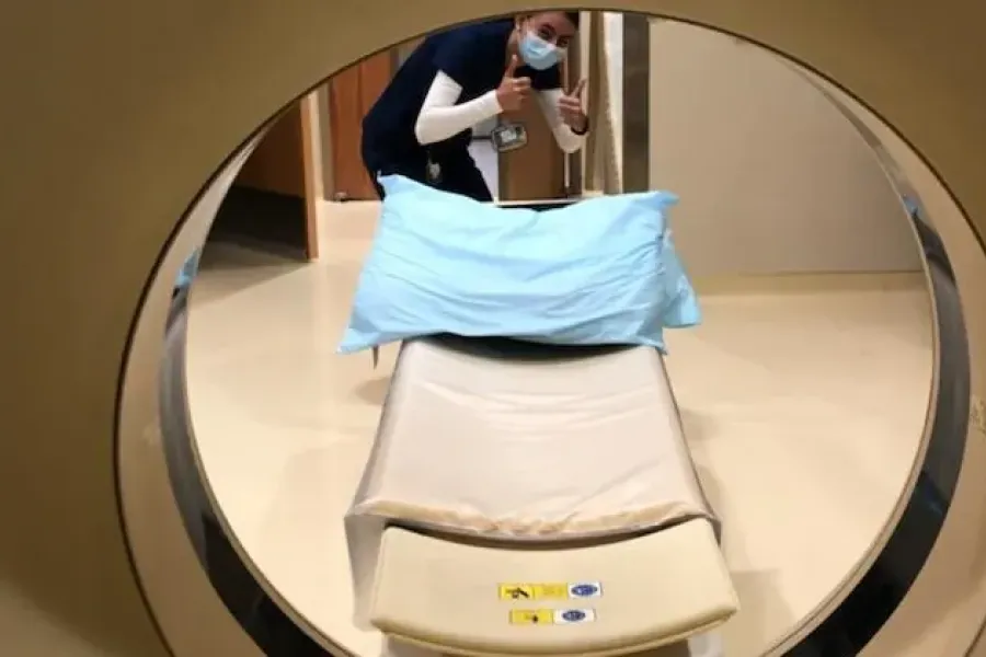 Picture taking from inside MRI machine looking out at student with thumbs up.