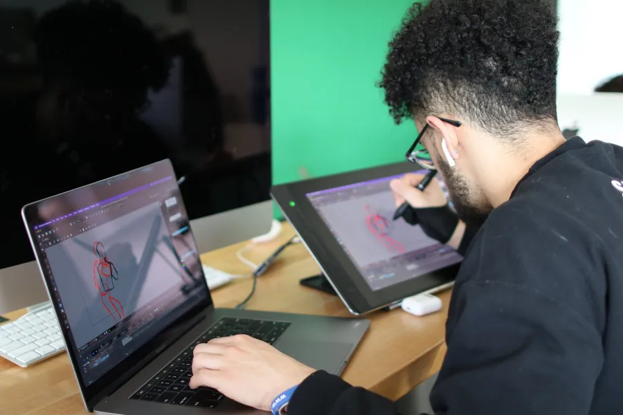 A student working on a computer and drawing tablet.