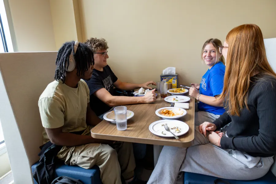 Four students enjoying food in the dining hall.
