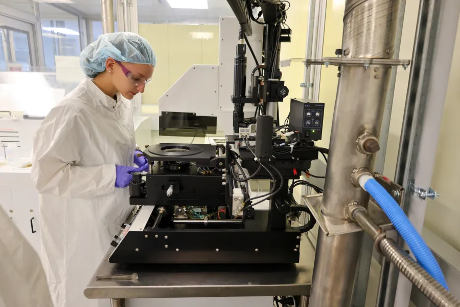A student working on equipment in a cleanroom lab.
