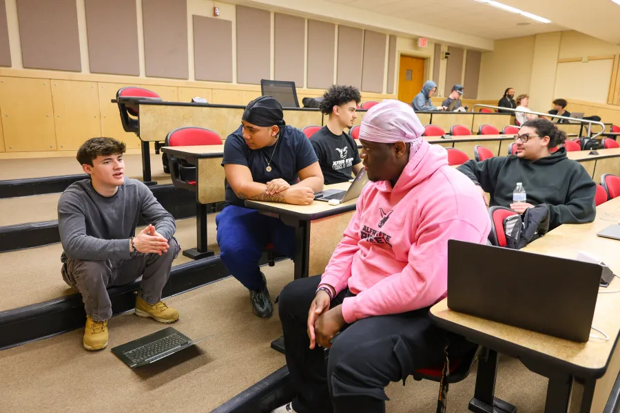 a group of students talking in a small lecture hall