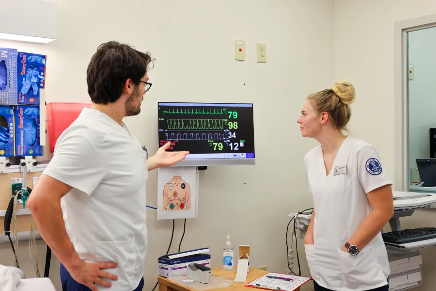 Two nursing students reviewing a monitor