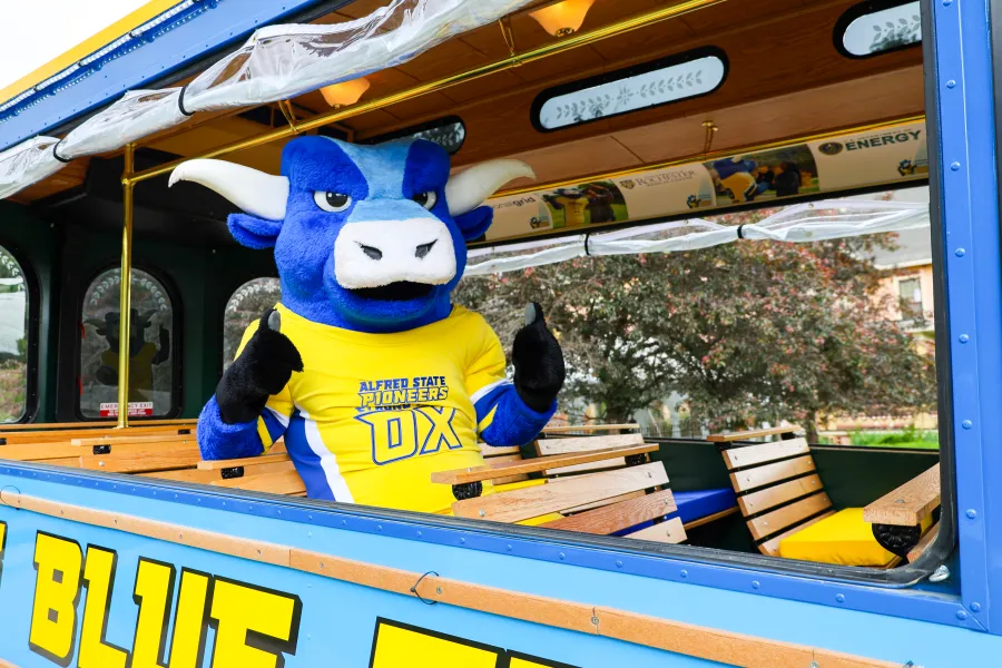 Alfred State's mascot, Big Blue, sitting in a blue trolley.