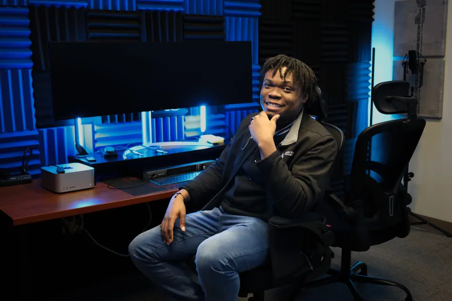 A student sitting in a podcasting studio with blue led lights.