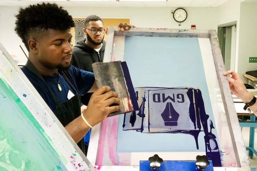 A student screenprinting a logo design.