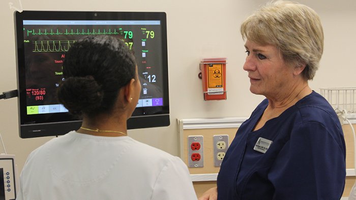 An Alfred State nursing student works with a professor during a skills lab.
