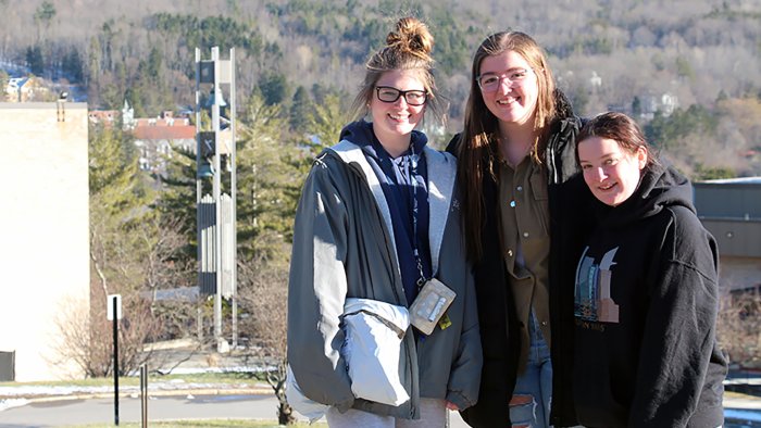 Alfred State students pose for a picture with the bell tower in the background.