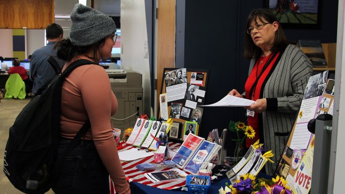 An Alfred State student speaks with a representative from the League of Women Voters during the Douglass Day celebration.