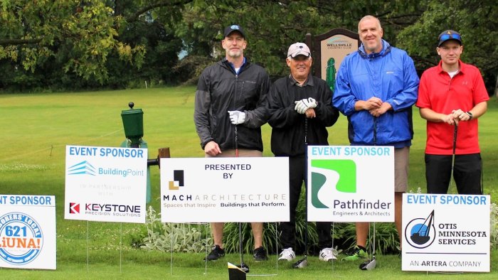 A foursome stands in front of tournament sponsor signs at the Alfred State Golf Tournament