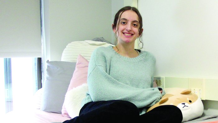 Gabriela Leite sits on her bed in her dorm room