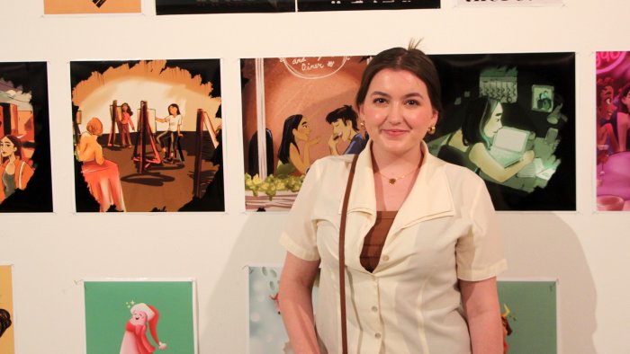 student stands in front of her artwork 