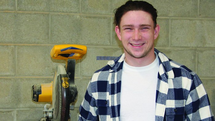 Thad Grierson stands in front of a saw in a building trades lab.