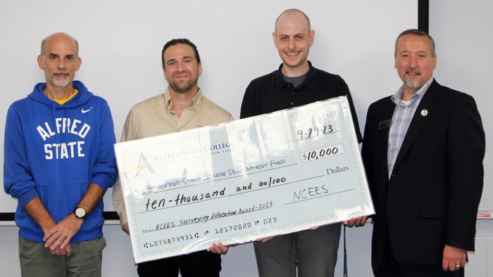 Alfred State's surveying and geomatics engineering technology program won $10,000 from the National Council of Examiners for Engineering and Surveying (NCEES). Pictured receiving the check (from L to R): Assistant Professor Richard Carlson, Christian Cernauskas, marketing communications outreach strategist for NCEES, Instructor Nick Ford, and Dean of the School of Architecture, Management & Engineering Technology John Williams.