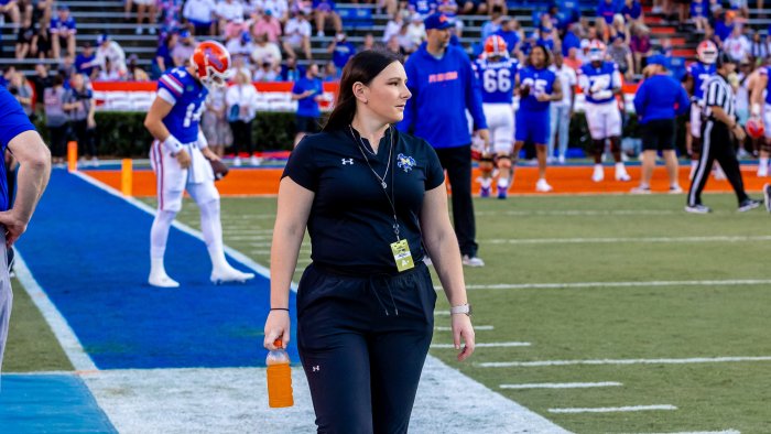 Alfred State alum Kelsey Curry walks the sideline prior to the start of a McNeese State football game at Florida.