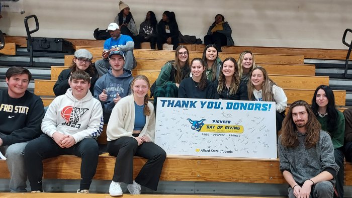 students sitting in the bleachers with a thank you banner.