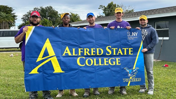 A group of Alfred State students hold a college sign