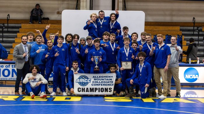 Alfred State wrestling team poses with championship banner and trophy