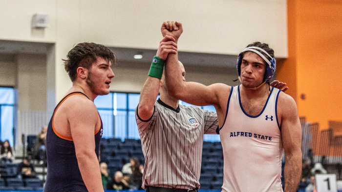 A wrestler has his arm raised in victory