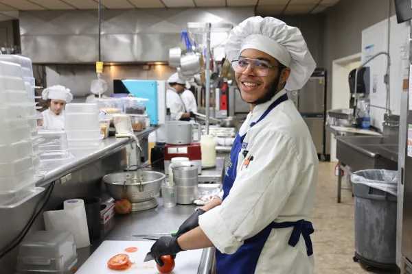 A student cutting vegetables in the culinary kitchen
