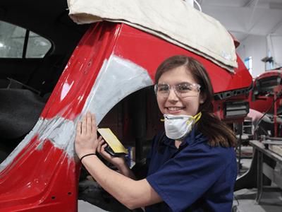 student with a mask near a red car