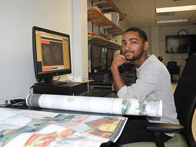 Caleb Boyce-Wright sitting at a desk with computer and papers
